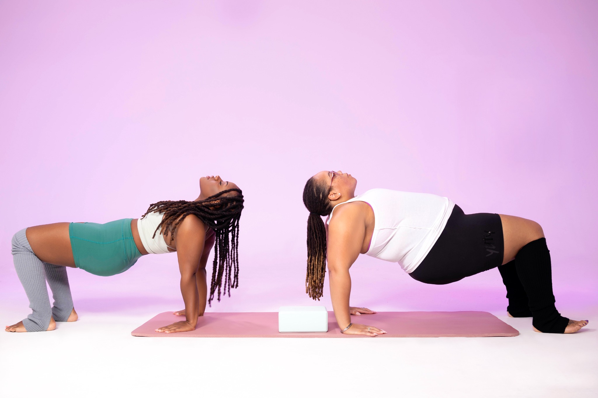 Coco and another woman practicing a movement pose side by side
